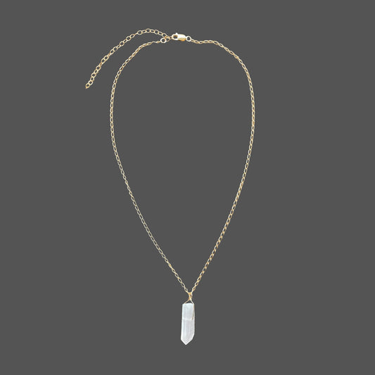 Gemstone pendant necklace with raw  clear quartz point pendant on a delicate gold chain. Shown alone on plain background.