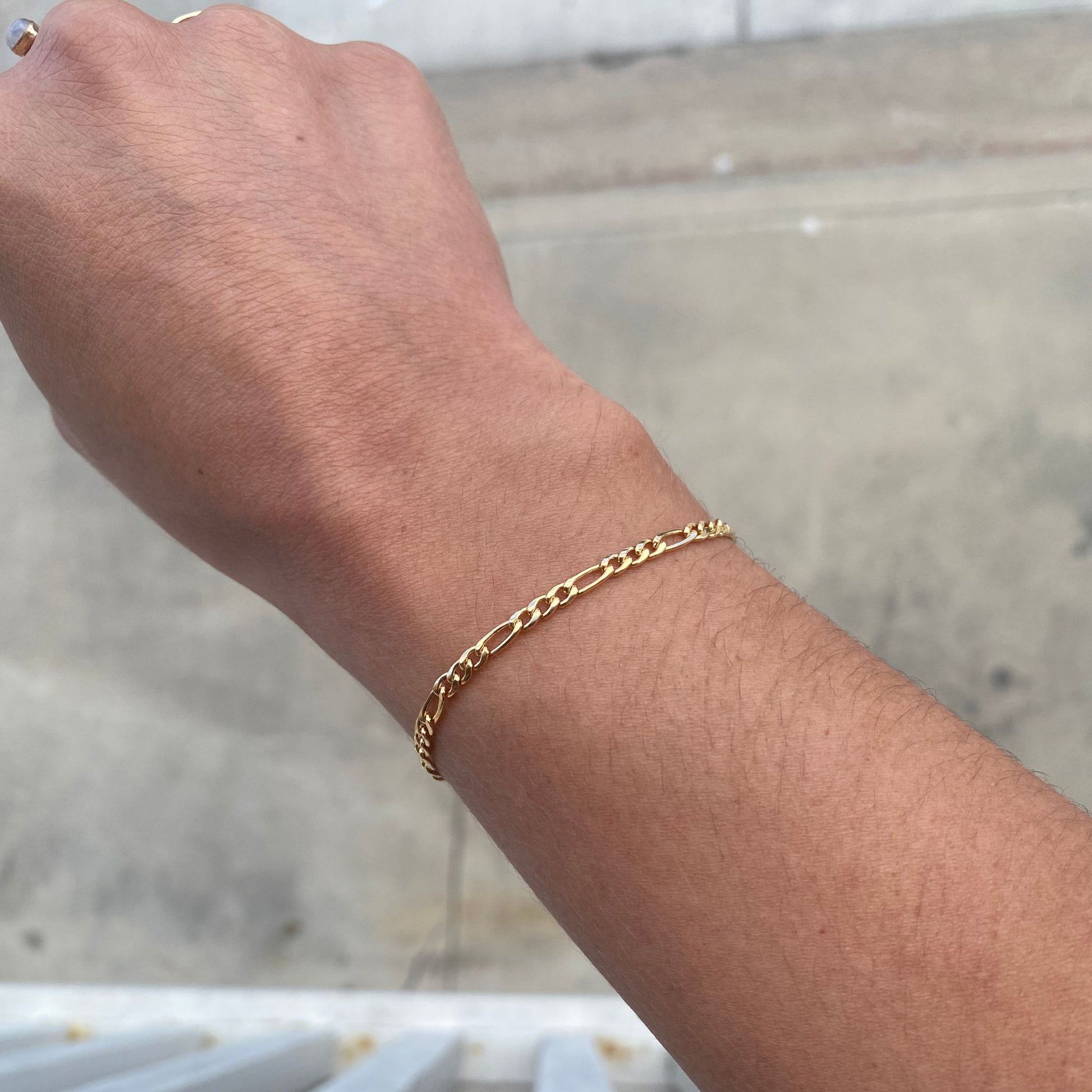 Figaro chain bracelet shown on model.