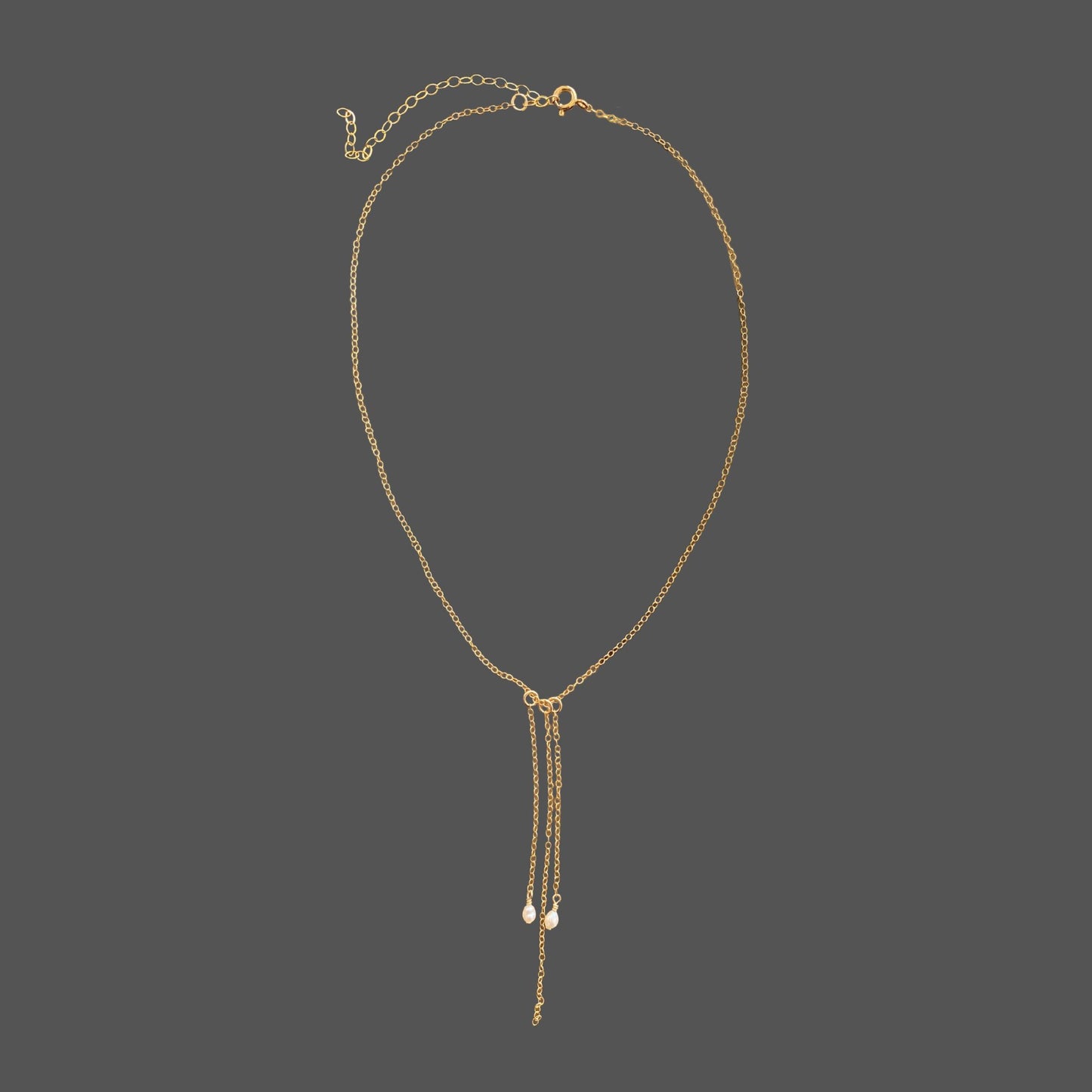 Pearl necklace with gold chain featuring two rice pearls and three cascading chain dangles. Shown alone on a plain background.