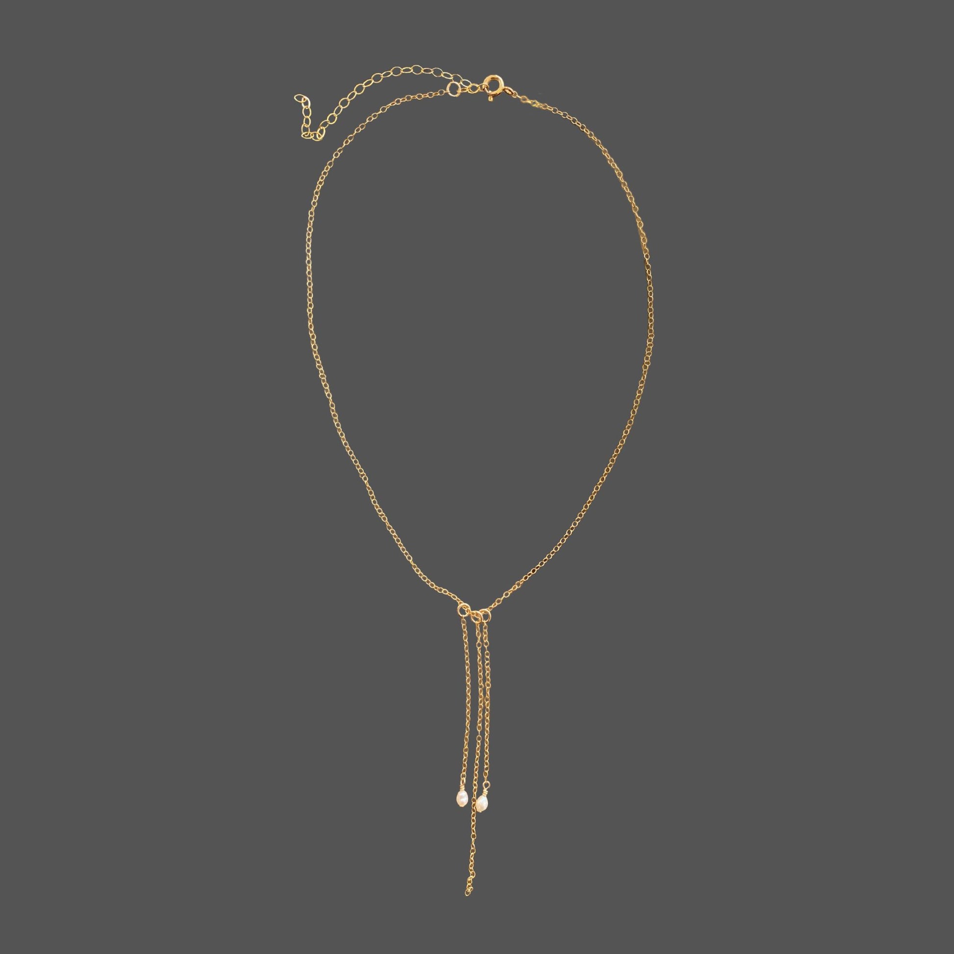 Pearl necklace with gold chain featuring two rice pearls and three cascading chain dangles. Shown alone on a plain background.