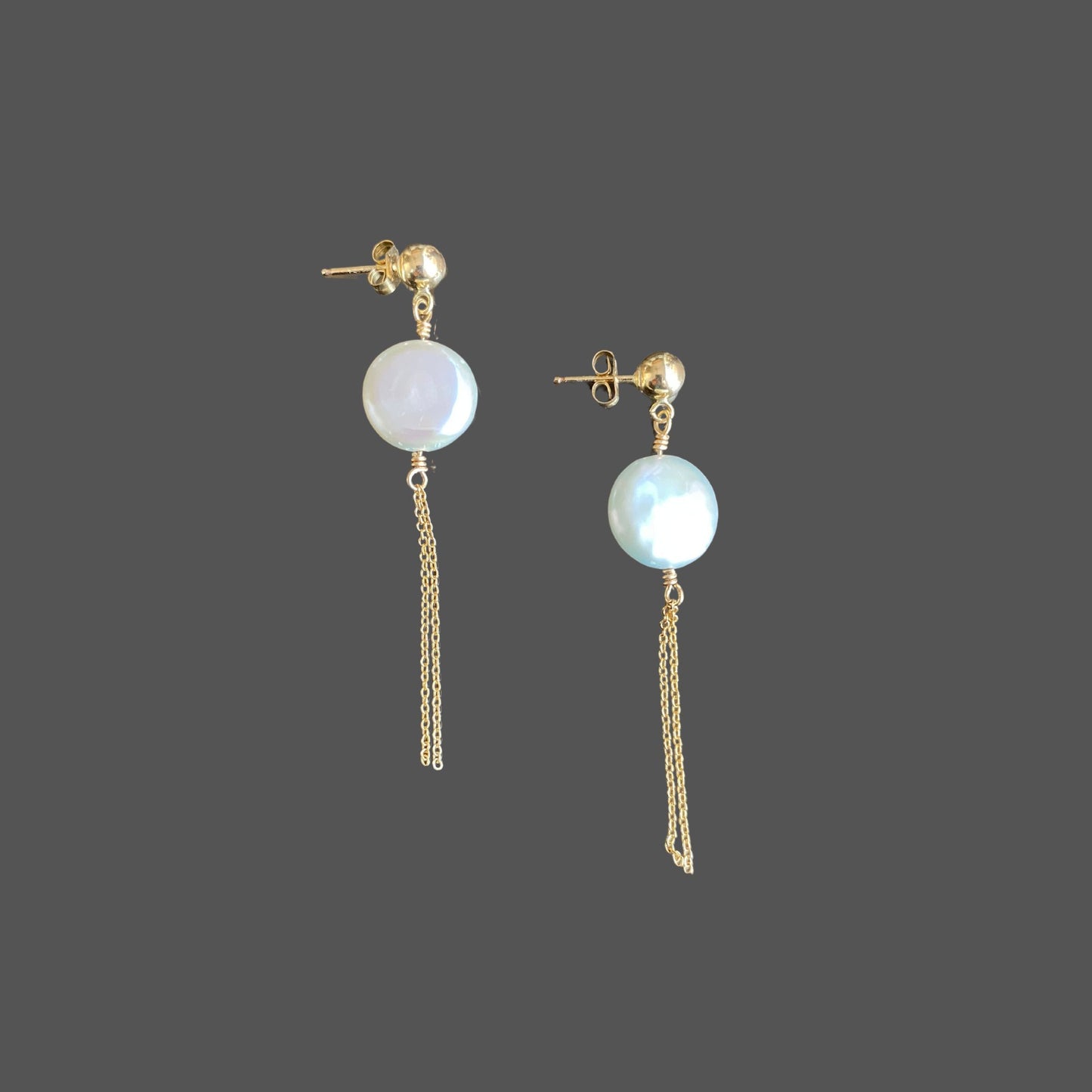 Side view of stud earrings with a gold ball stud, featuring a round coin pearl and two strands of gold chain hanging below the pearl.