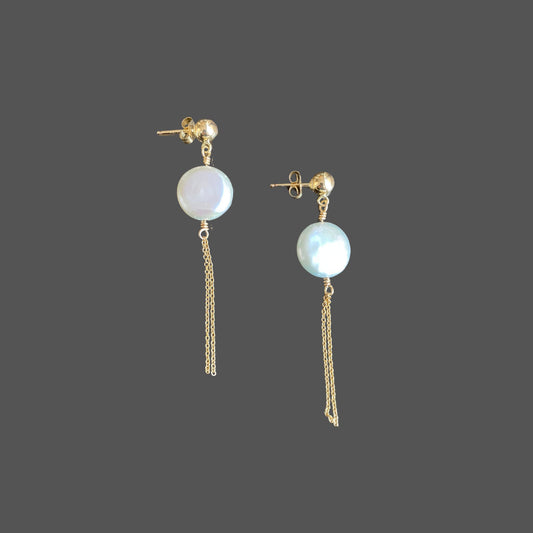 Side view of stud earrings with a gold ball stud, featuring a round coin pearl and two strands of gold chain hanging below the pearl.
