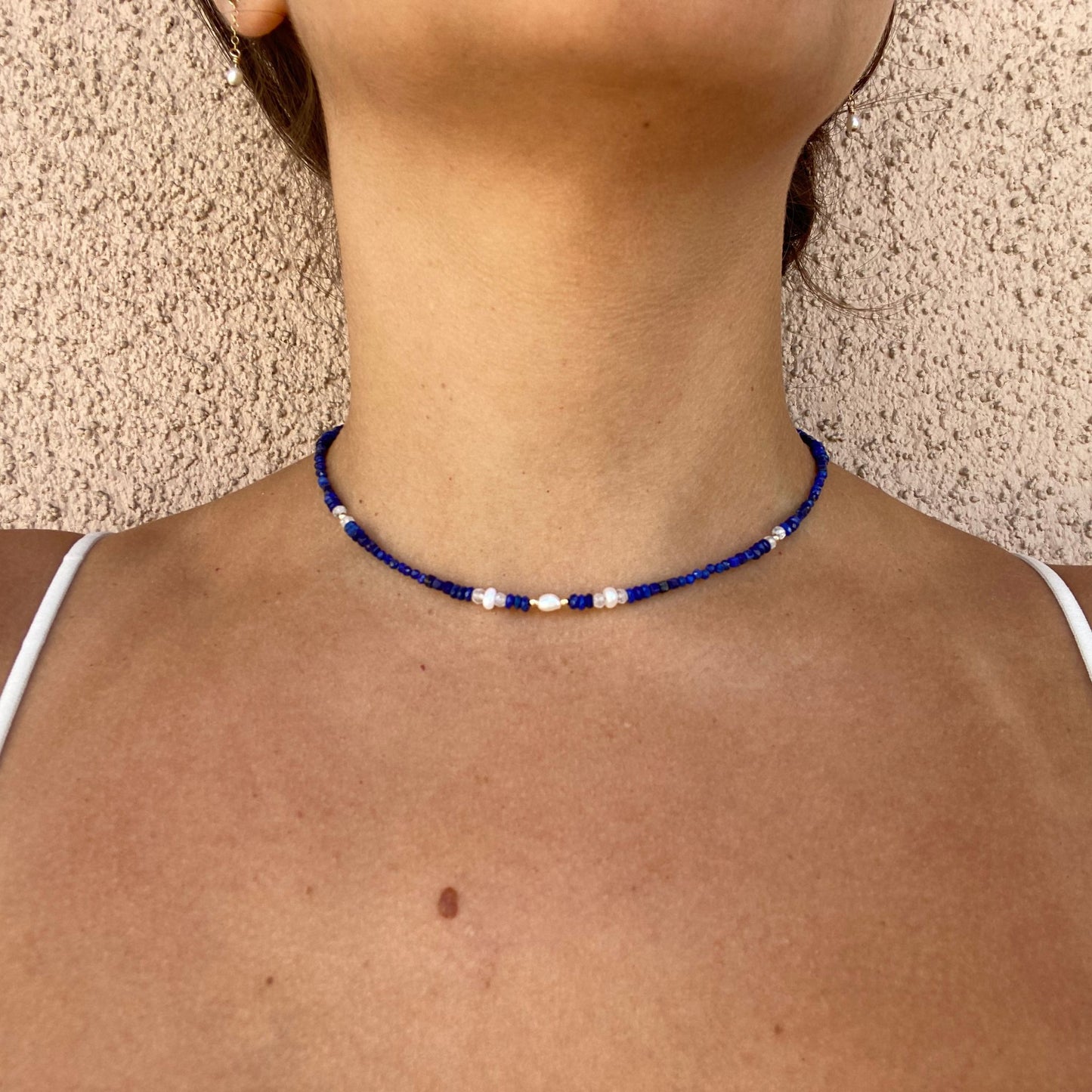Pearl and gemstone necklace shown on model, with lapis lazuli, pearls, and moonstone.