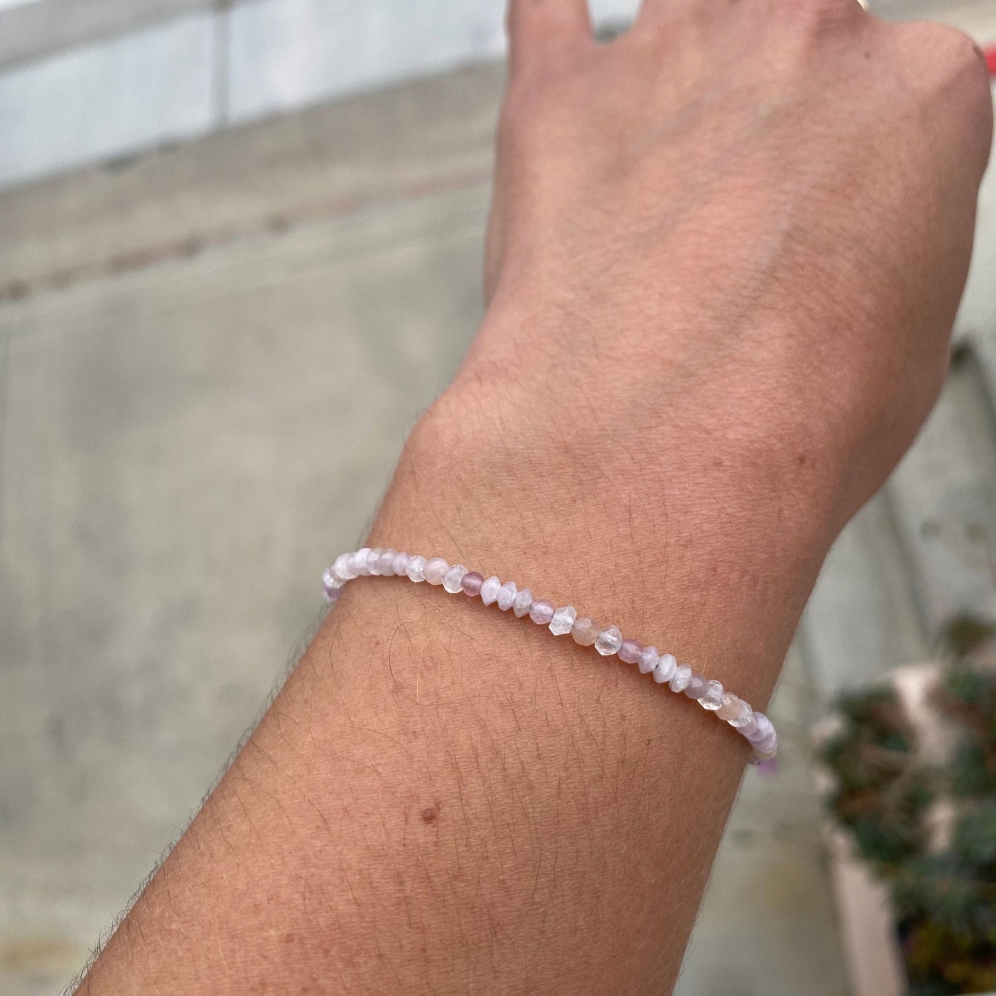 Model shown wearing a beaded gemstone bracelet featuring blush-toned rose quartz, kunzite, and moonstone. Only the model's wrist is visible.