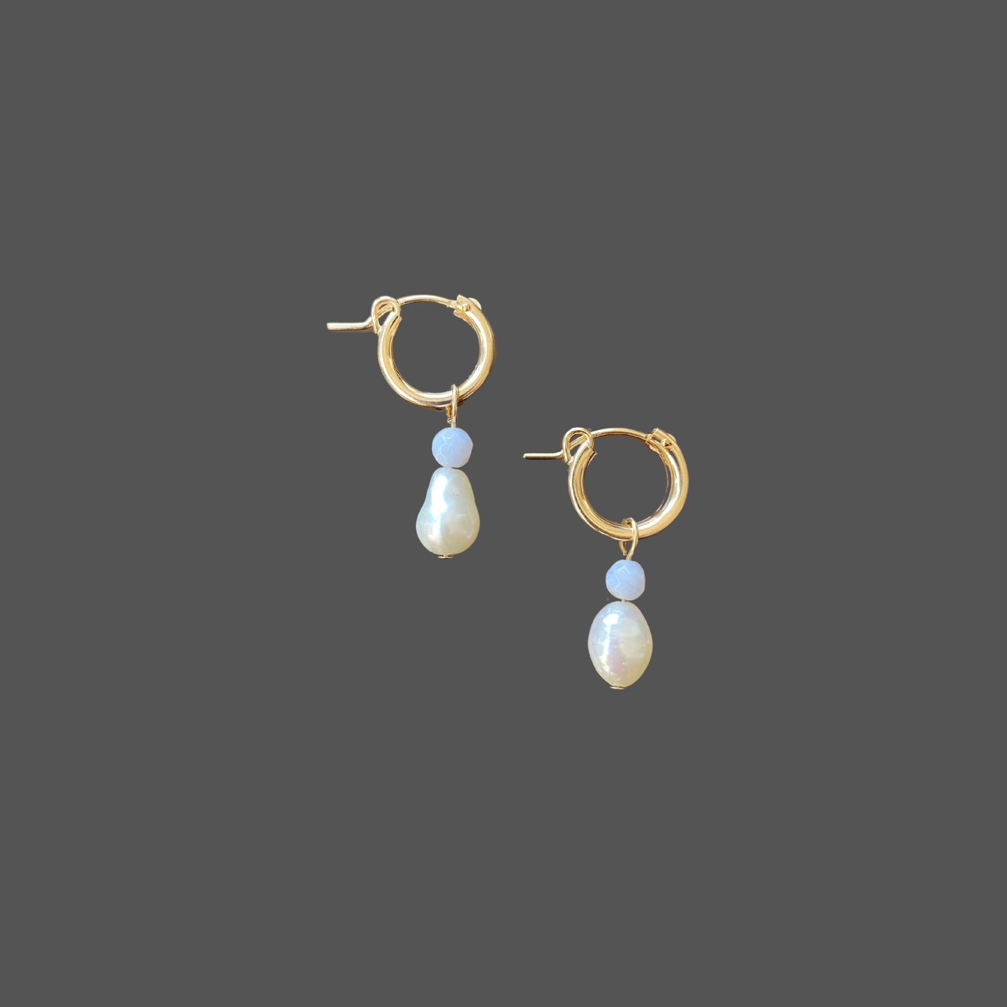 Side view of pearl earrings featuring gold hoops with charms of blue lace agate and freshwater pearls.