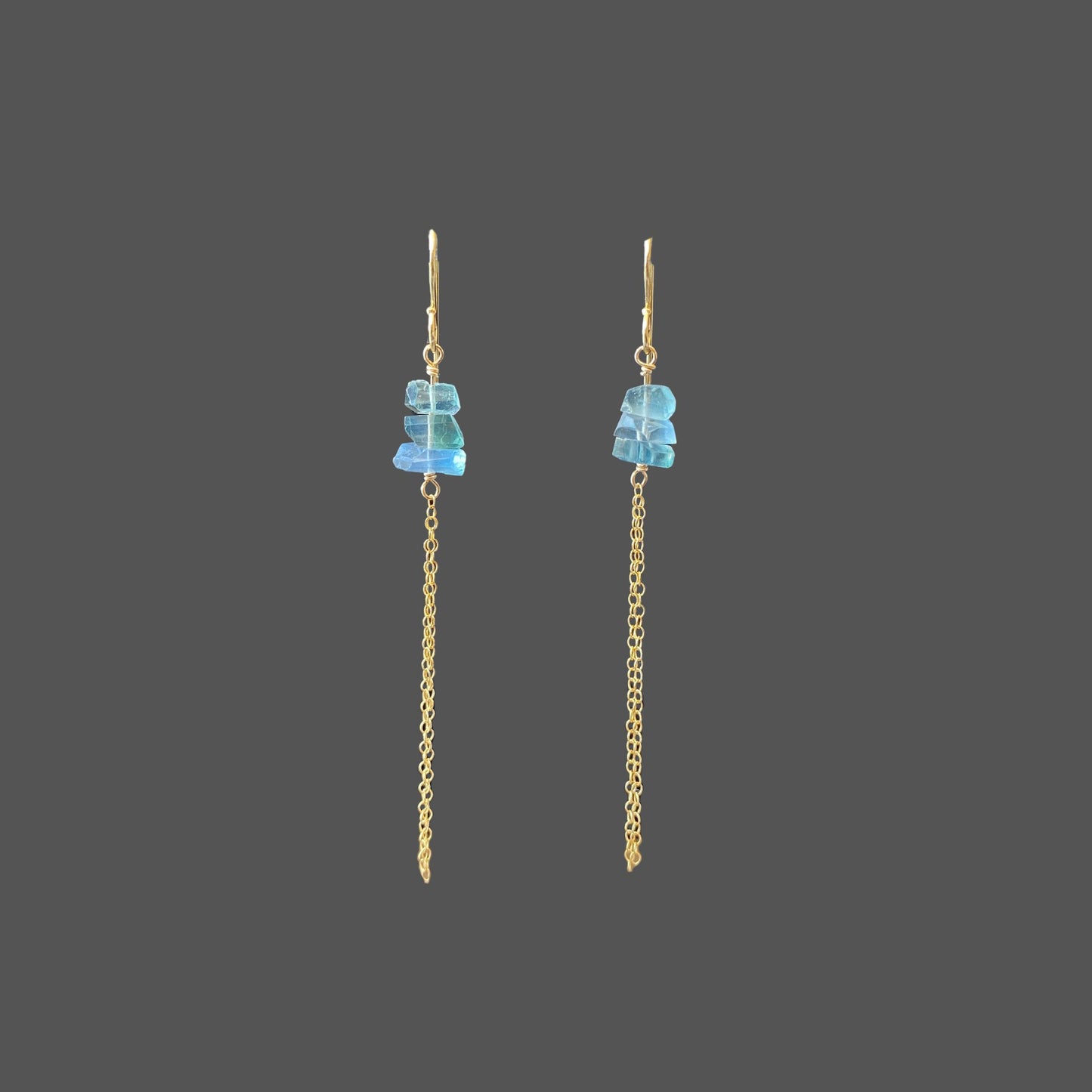 Front view of long earrings featuring three transparent blue-green fluorite stones, with delicate gold chains hanging below.