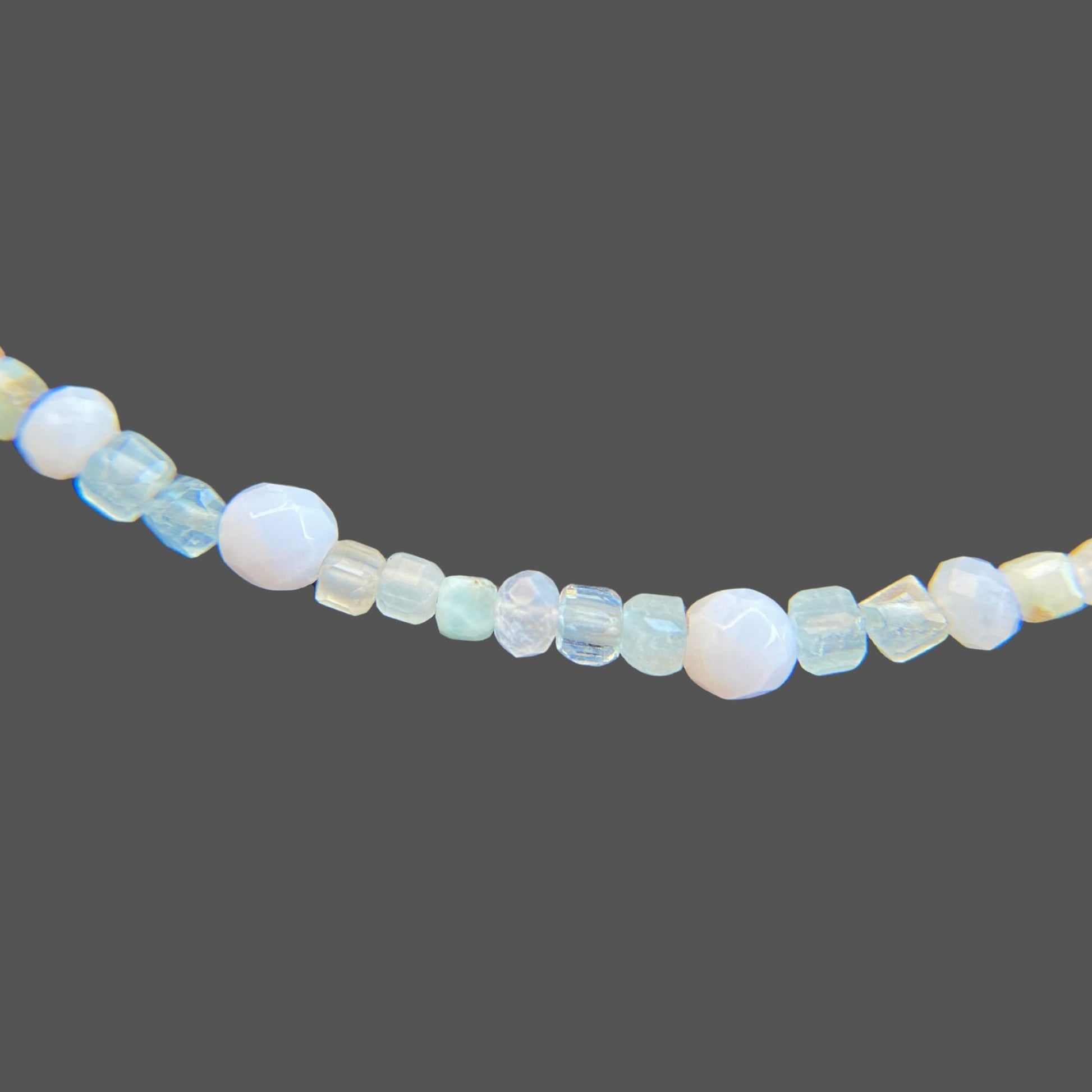 Close-up view of gemstone necklace, featuring aquamarine, blue lace agate, larimar, and sunstone gems in soft blue hues.