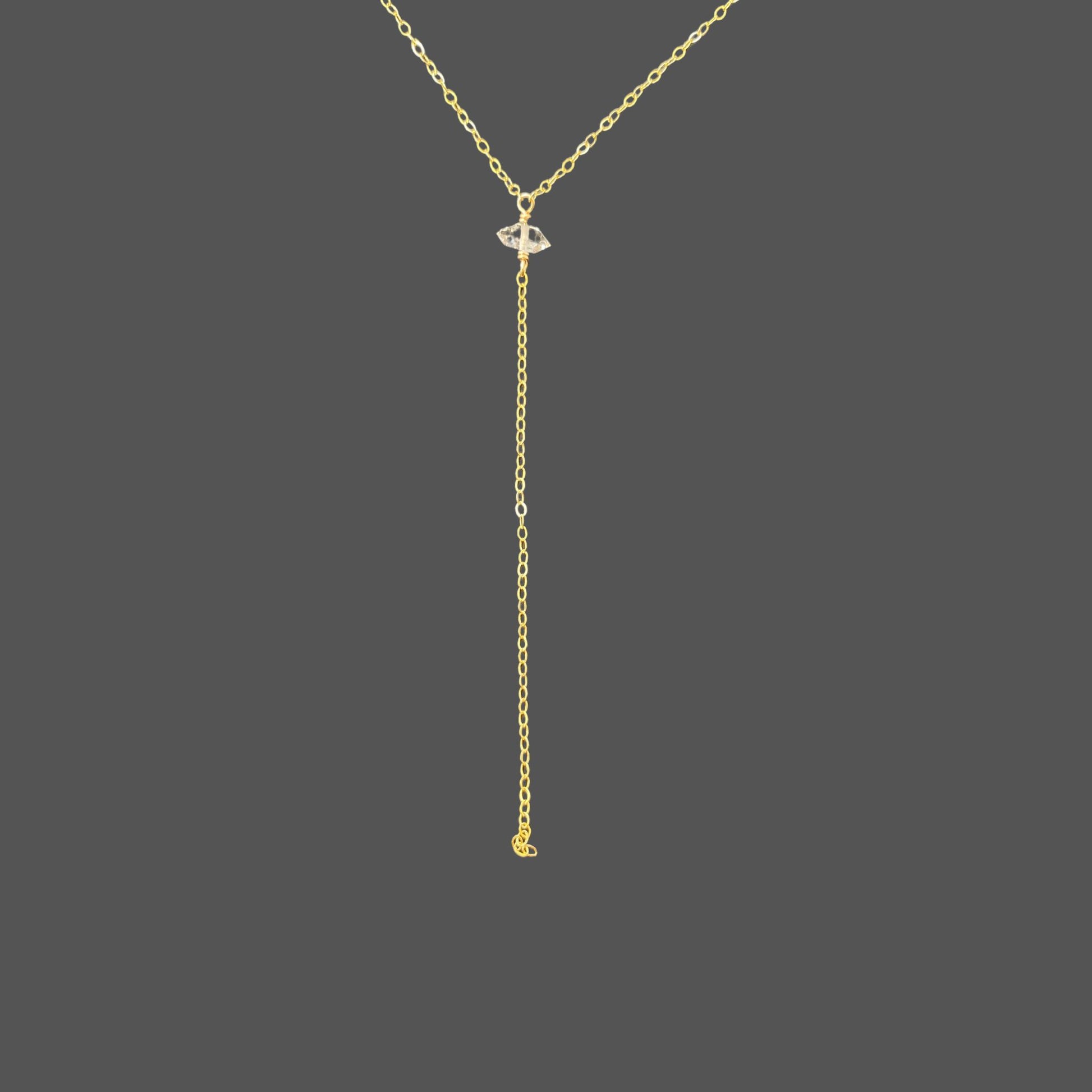 Close-up of herkimer diamond pendant and cascading chain on gold necklace. Shown alone on plain background.