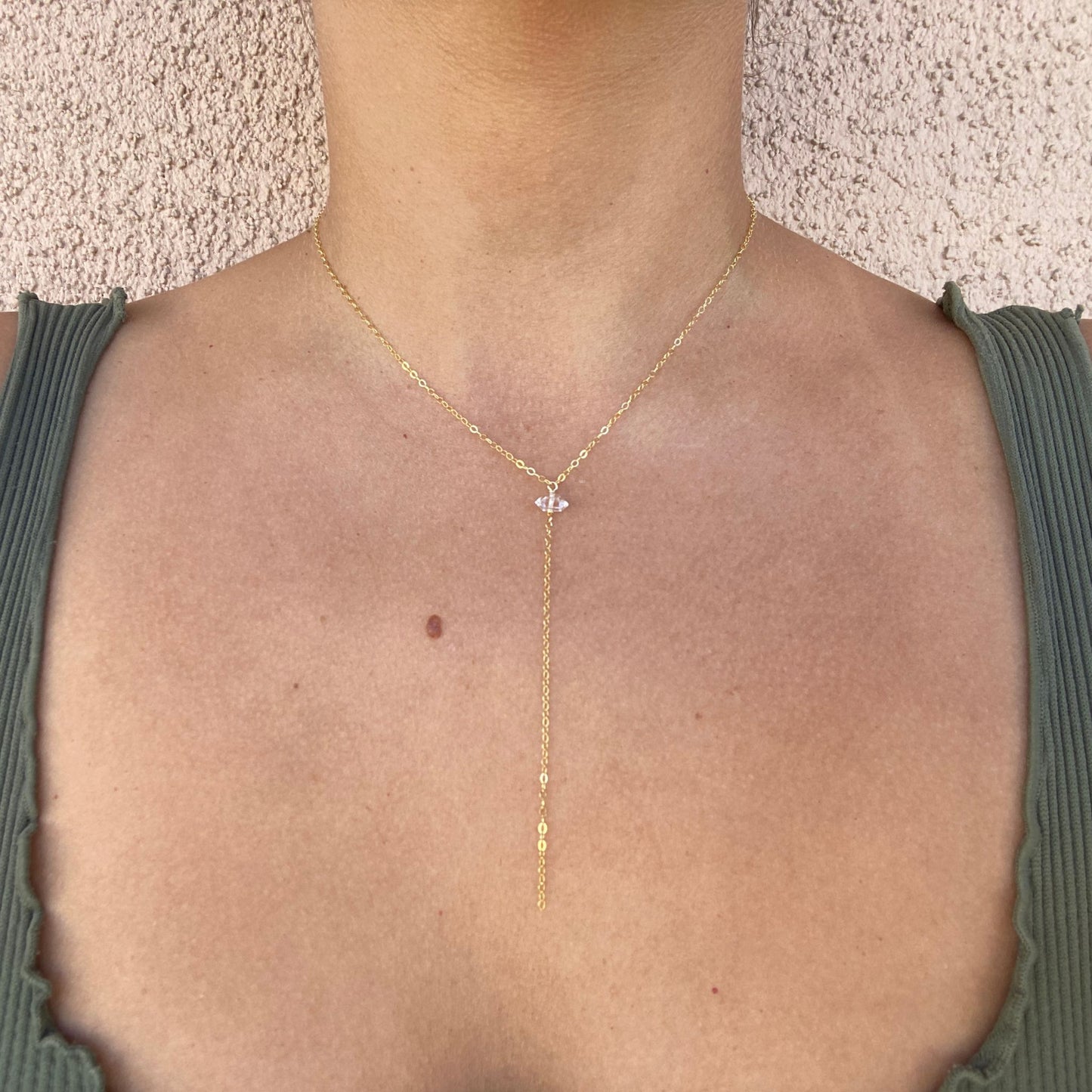 Minimal pendant necklace shown on model. Features gold chain with Herkimer diamond pendant and long chain hanging below pendant.