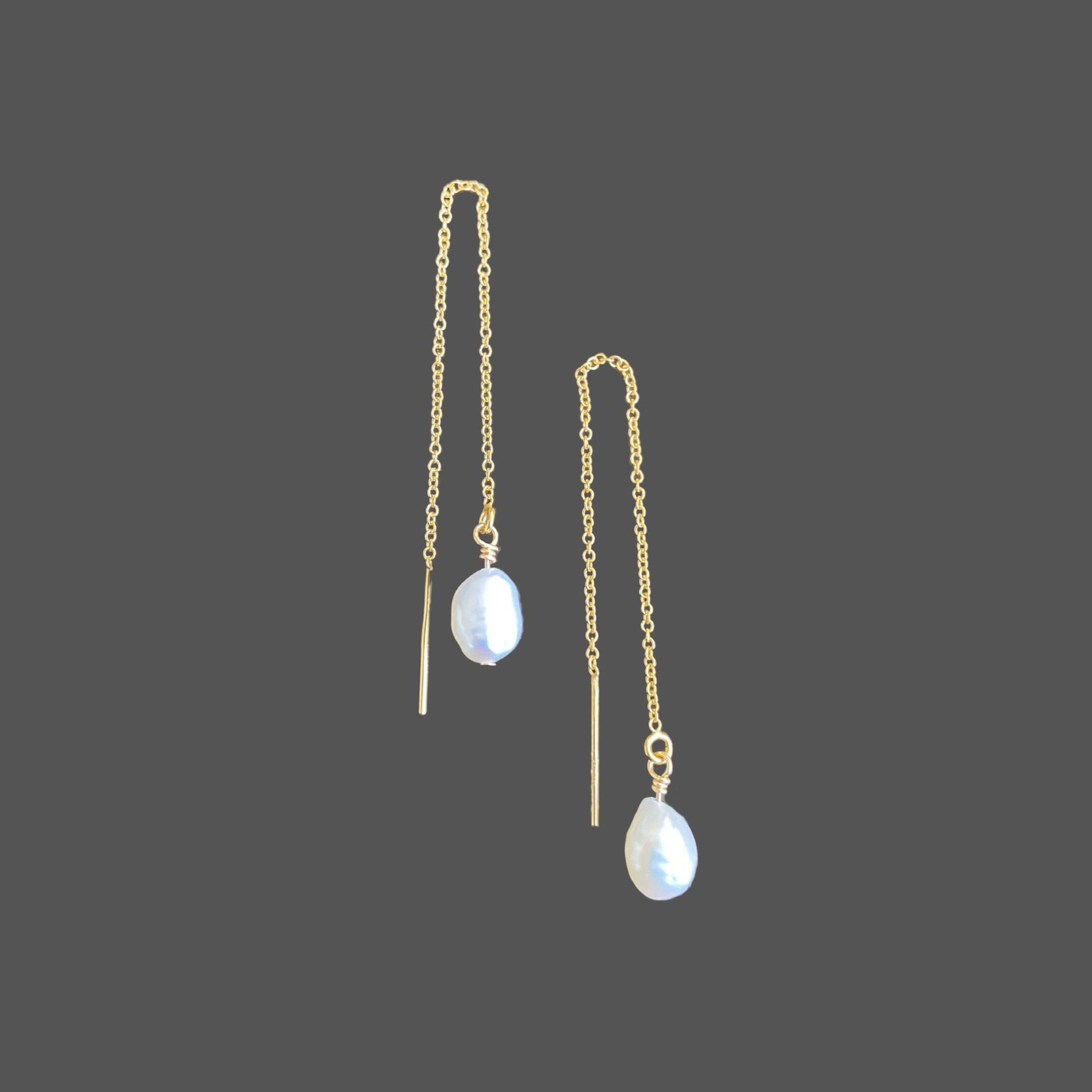 Minimal pearl earring threaders with gold chain and a single lustrous pearl, displayed against a neutral background.