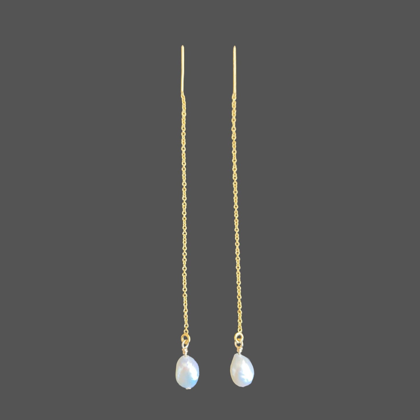 Minimal pearl earring threaders with gold chain and a single lustrous pearl, displayed against a neutral background.