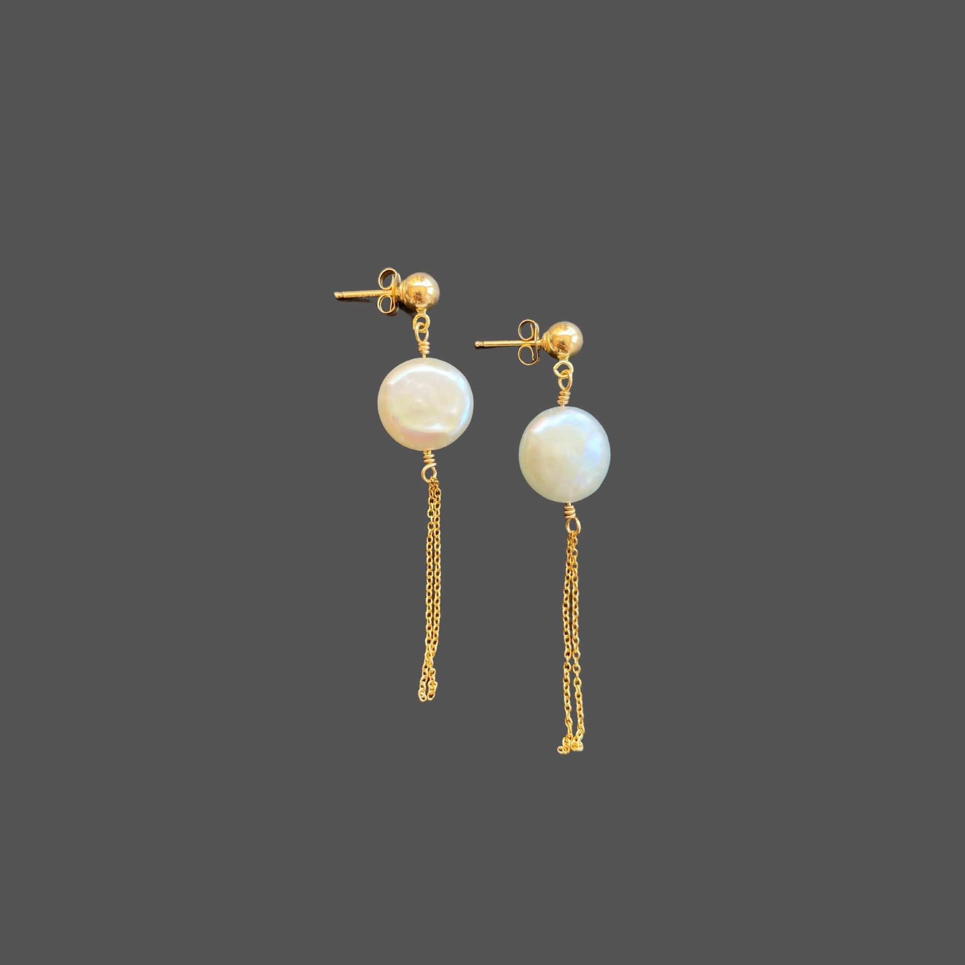 Side view of stud earrings with a gold ball stud, featuring a round coin pearl and two strands of gold chain hanging below the pearl.