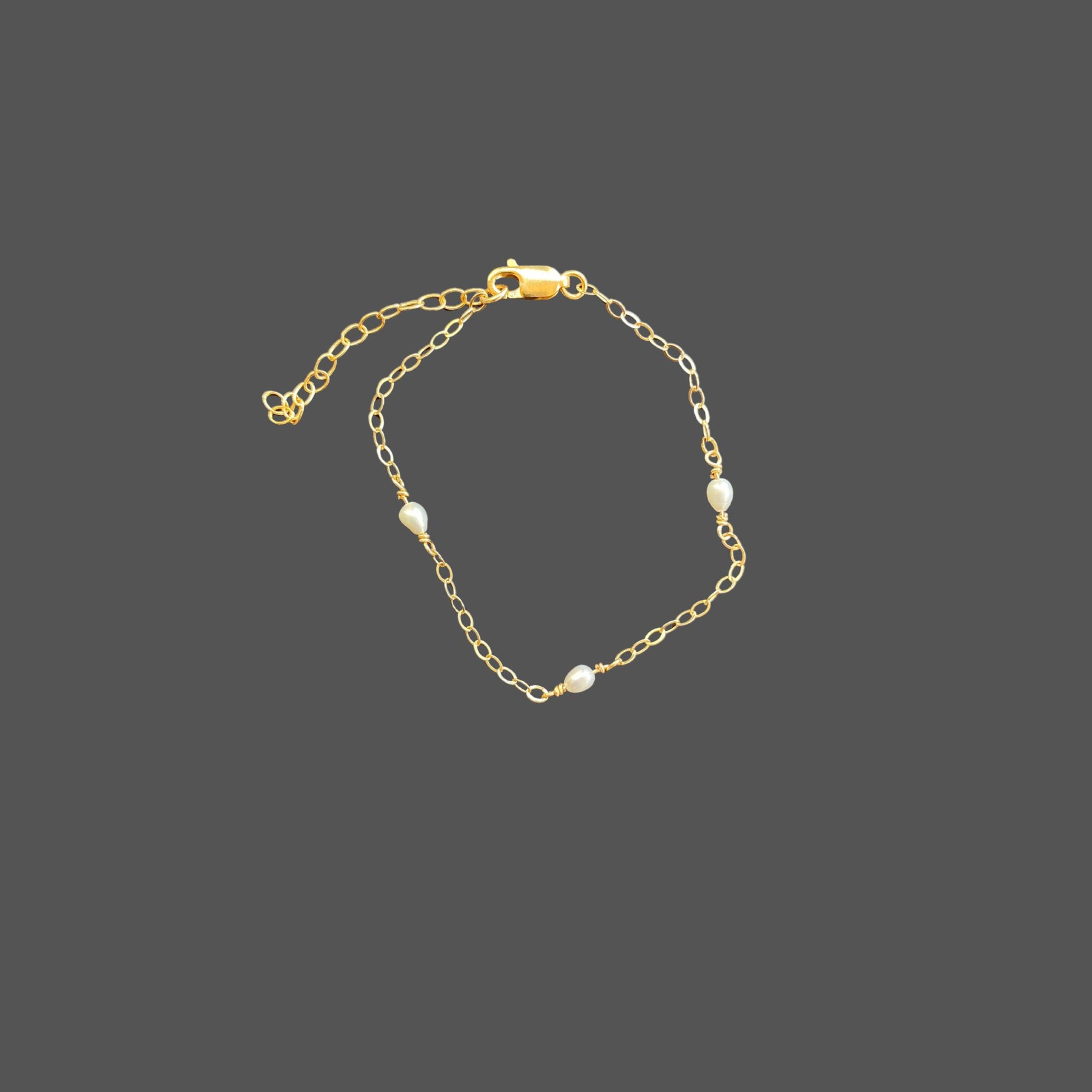 Pearl bracelet with three small rice pearls equally spaced along the gold chain.