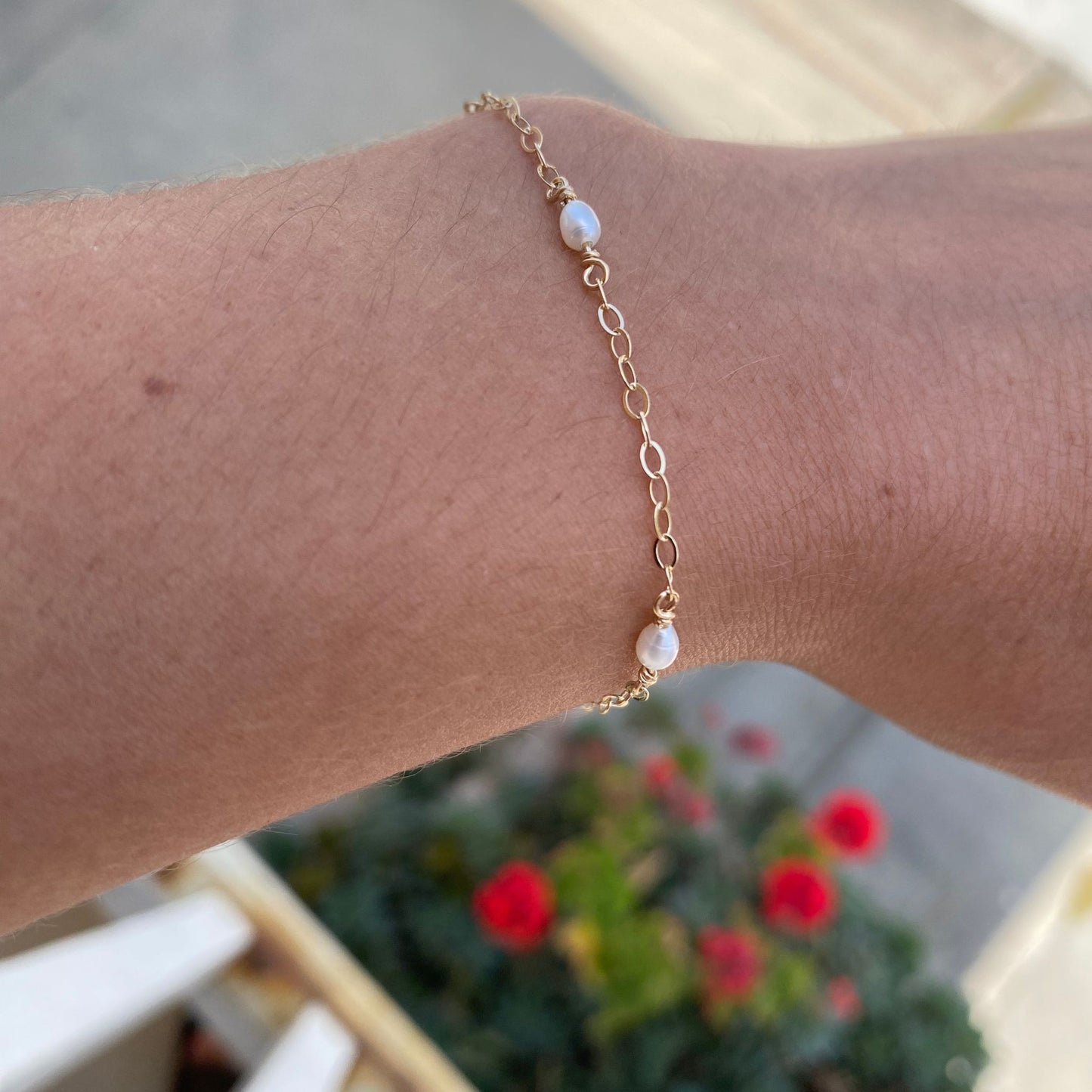 Gold chain bracelet with pearls shown on model. Only the model’s wrist is visible.