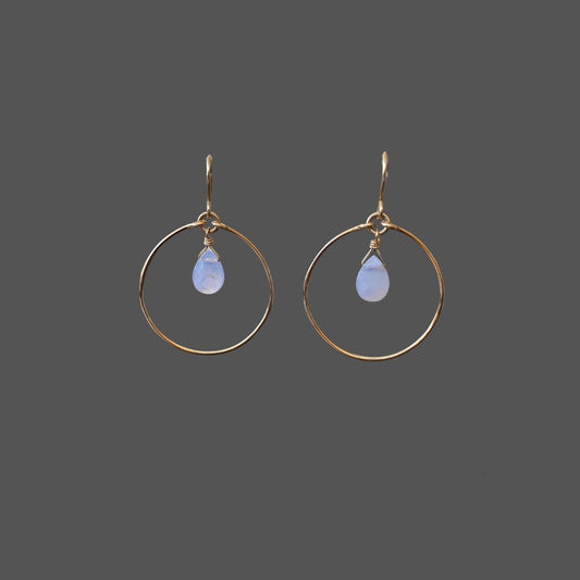 Front view of gold hoop earrings featuring a blue chalcedony gemstone hanging from the top center of the hoop.