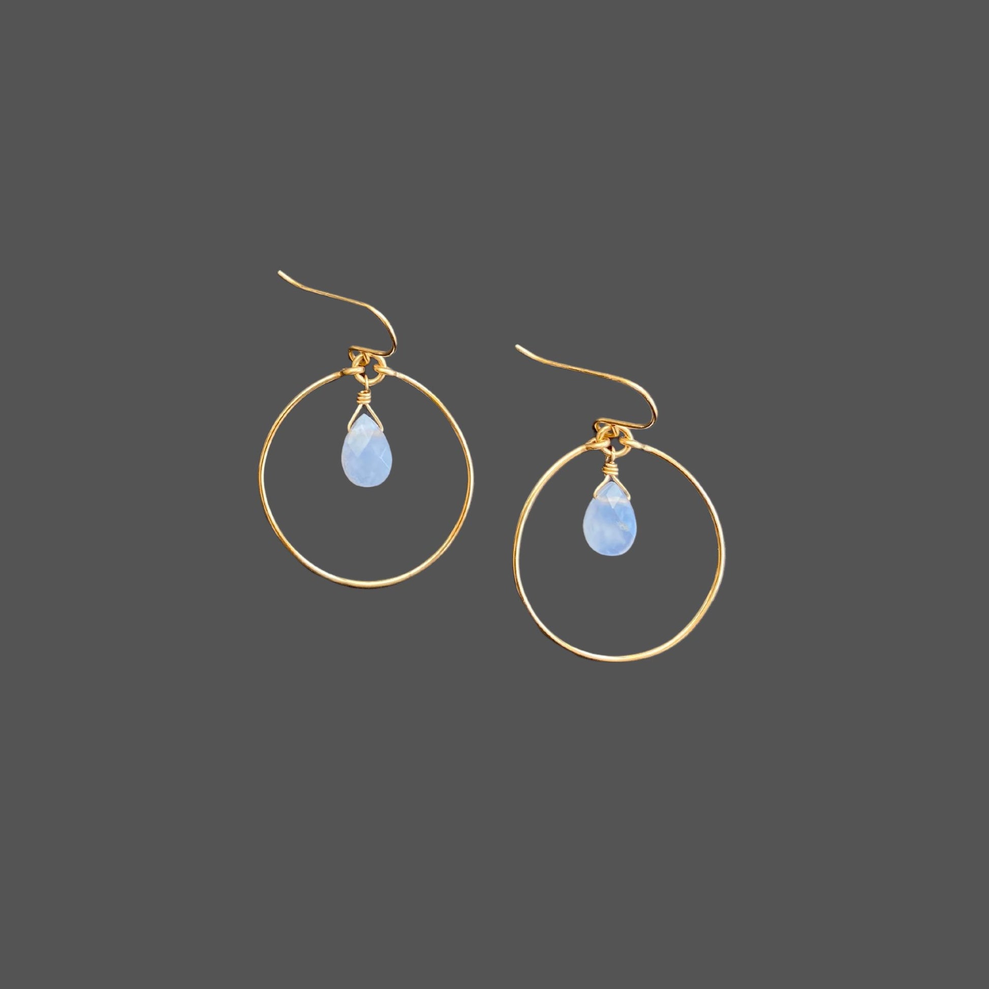 Gold hoop earrings with French earwires, featuring a blue chalcedony gemstone hanging from the top center of the hoop.