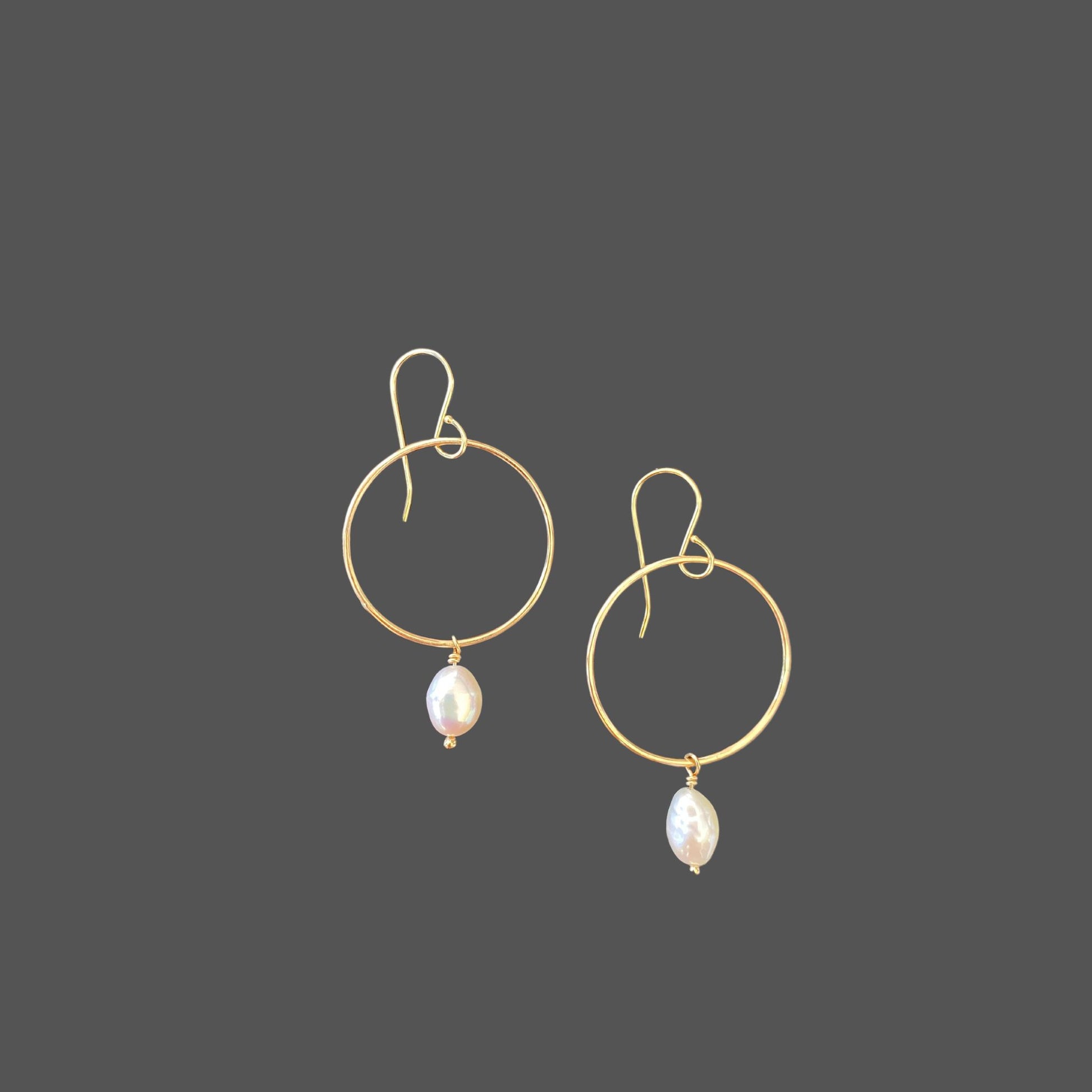 Pearl earrings with gold hoops and French earwires, with a small freshwater pearl hanging from the bottom of the hoop.