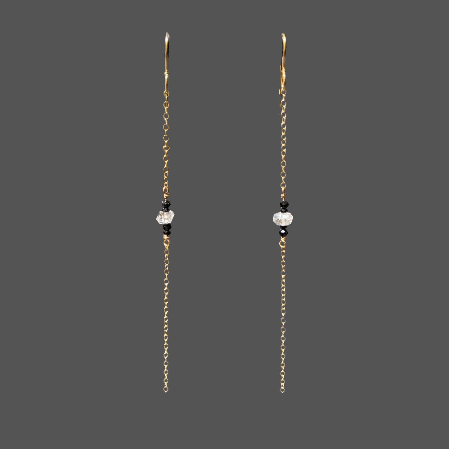 Long earrings shown alone on plain background. A single strand of gold chain with herkimer diamond and black tourmaline gems at midpoint of the chain.