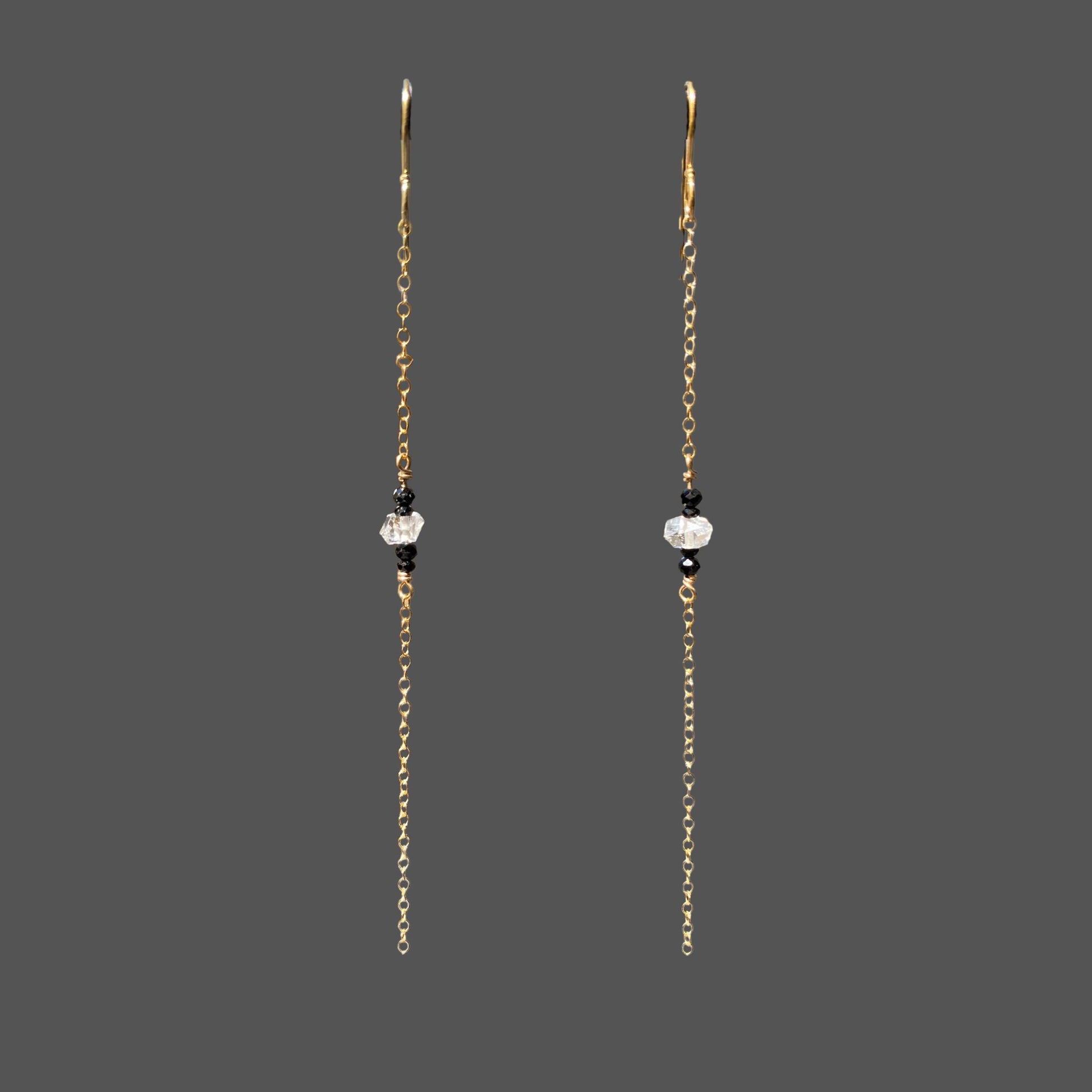 Long earrings shown alone on plain background. A single strand of gold chain with herkimer diamond and black tourmaline gems at midpoint of the chain.