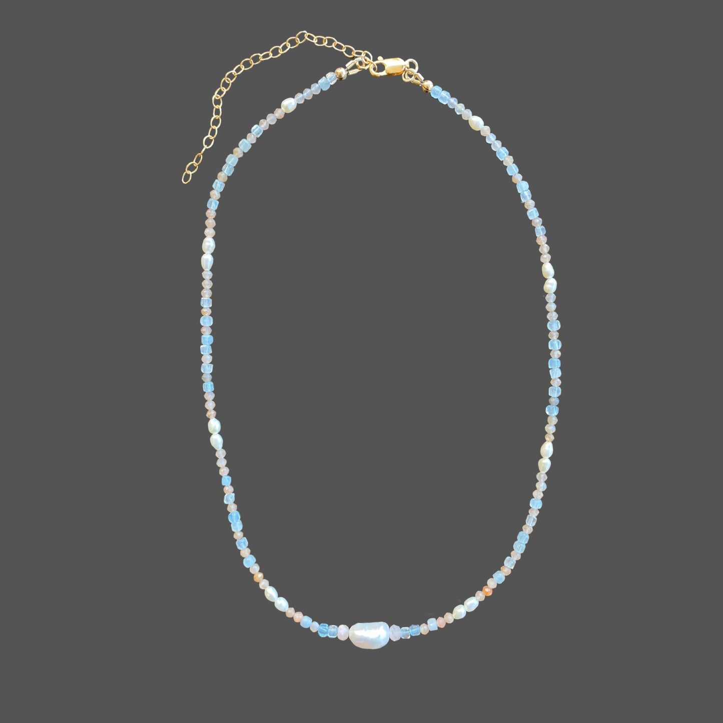 Beaded pearl necklace with freshwater pearls, and aquamarine and sunstone gems in the colors of sunset. Shown alone on plain background.