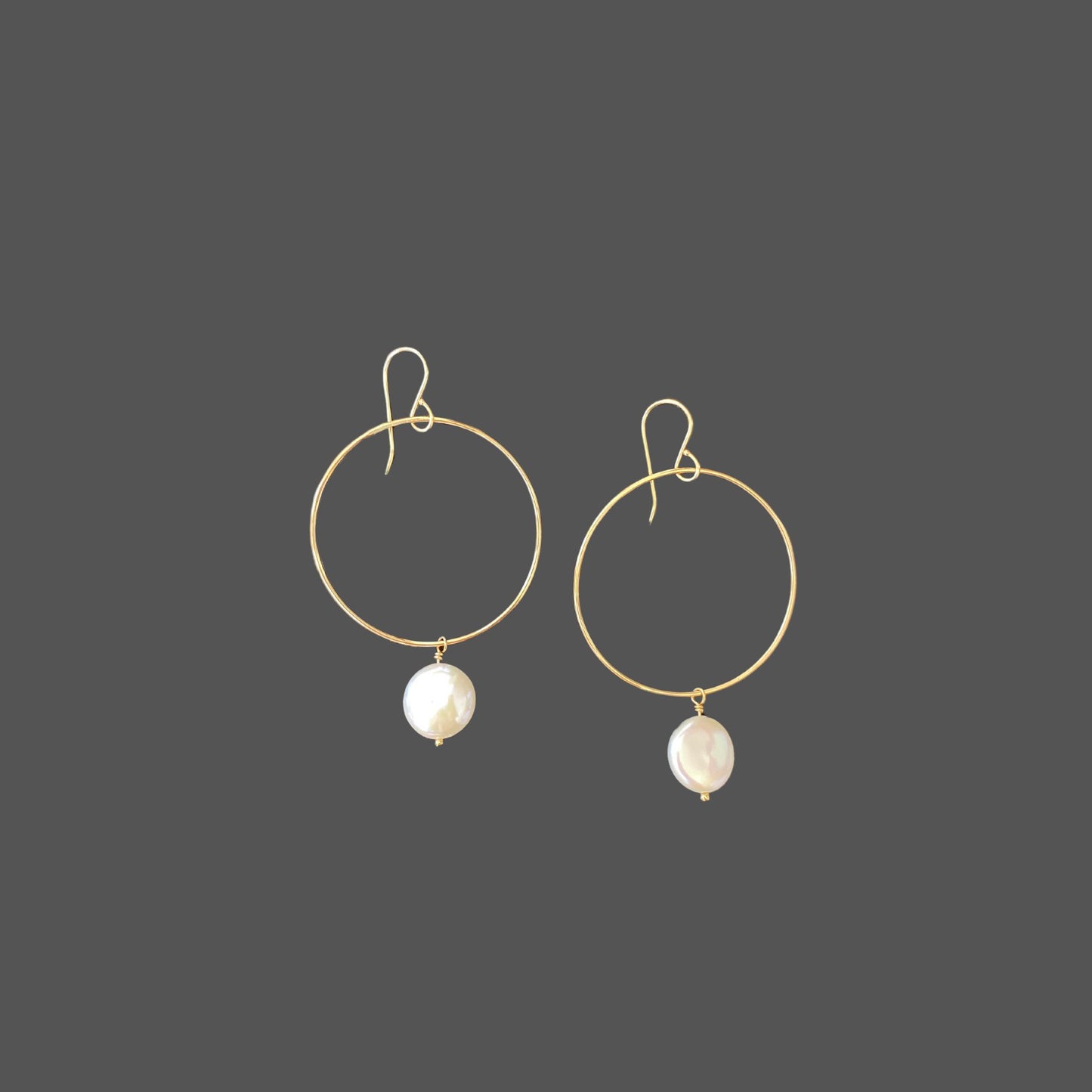 Pearl earrings with gold hoops and French earwires, with a round freshwater coin pearl hanging from the bottom of the hoop.